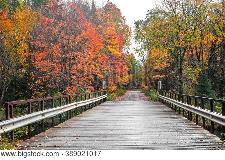 Small wooden bridge on Peshekee river in Van Riper state park in Michigan upper peninsula surrounded with fall foliage