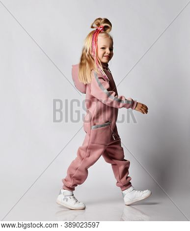 Frolic Sly Smiling Blonde Kid Girl With Modern Hairstyle And Colorful Braids Wearing Pink Jumpsuit W