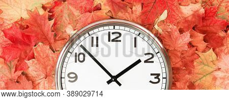 Plain Wall Clock In The Center Of Autumn Orange Red Leaves And Fall Foliage. Two Oclock. Copy Space,