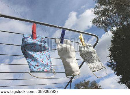 Three Reusable Cloth Face Masks Drying On A Washing Line Outdoors On A Sunny Day. Covid 19 Preventio