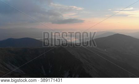 Foggy Sunrise In The Mountains. Gloomy Mountains Against The Background Of A Cloudy Mysterious Sky.