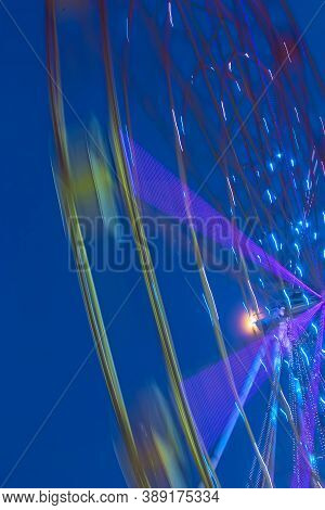 Carnival Ride Showing A Spinning Ferris Wheel In Action- Long Exposure Shot.