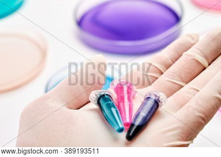 Eppendorf Tubes With Blue, Green And Pink Liquids In The Hand Of Scientist On The Background Of Petr