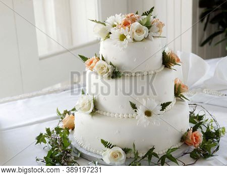 The white Christmas cake decorated with roses on display by the window looks so beautiful