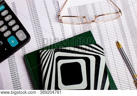 Calculator, Glasses, Pen And Notepads On The Background Of Reports On The Desktop. Business Concept