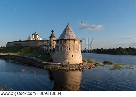 Pskov Kremlin View From River Pskova Creek. Towers, Wall And Trinity Cathedral On Background.
