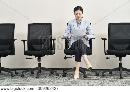 Young Asian Female Job Seeker Sitting In Chair Preparing For Interview While Waiting In Line