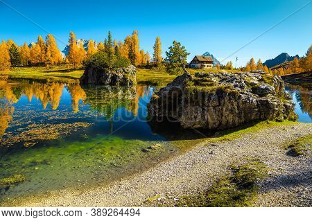 Amazing Colorful Autumn Forest With Spectacular Alpine Lake. Colorful Larches And Small Cute House O