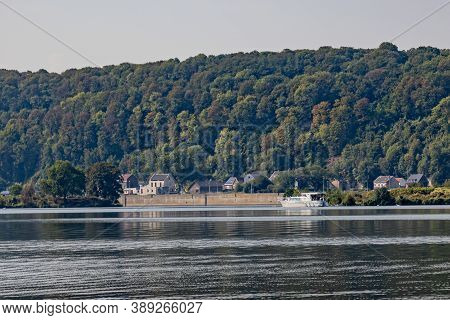 River Maas (meuse) With Its Calm Waters With A Boat Anchored In A Small Pier On Its Shore, House And