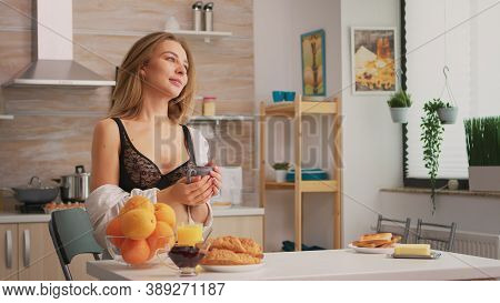 Attractive Woman In Black Ligerie Relaxing With Coffee During Breakfast Sitting In Kitchen And Smili