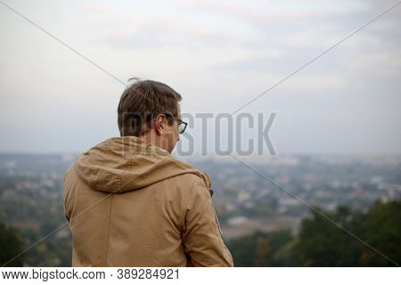 Man In Glasses And A Brown Jacket Looking At The Horizon
