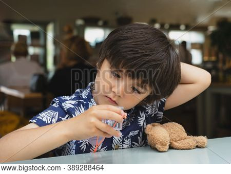 Portrait Of Curious Kid Looking At Plastic Bug Box And Playing With His Toy While Sitting In Cafe, C