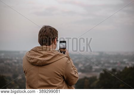 A Man Taking A Photo Of A Landscape Using His Phone
