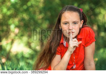 Hushing. Teengirl with her finger over her mouth.