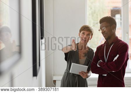 Waist Up Portrait Of Female Art Gallery Manager Instructing Assistant While Planning Exhibition In M