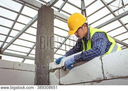 Bricklayer Builder Working With Autoclaved Aerated Concrete Blocks. Walling, Installing Bricks In Co