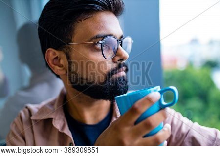 Arabian Man In Casual Dress Holning A Blue Cup And Looking Dreamly
