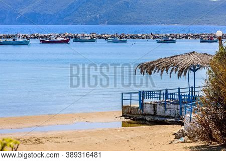 Beach Umbrella And Fishing Boats And Mountain View In Messinia, Peloponnese, Greece
