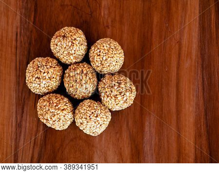 White Sesame Seed Balls Made With Heated Jiggery Against Wooden Background