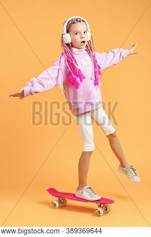Active And Happy Girl With Curly Hair, Headphones Having Fun With Penny Board, Smiling Face Stand Sk