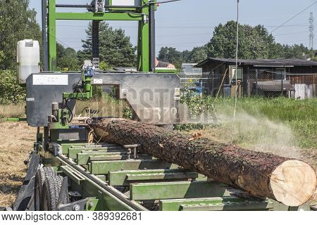 Mobile Sawing Equipment For Logs In The Open Air. Rural Landscape On A Sunny Day. Mobility And Work 