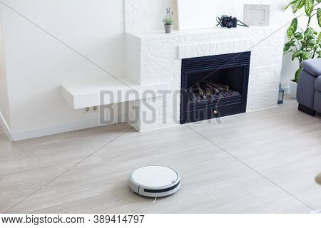 White Robot Vacuum Cleaner Cleans The Floor From Debris, Home Cleaning With An Electric Vacuum Clean