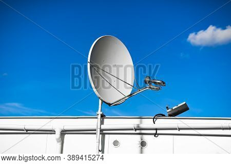 Sattelite Dish In The Blue Sky On The Roof Of The Industrial Building
