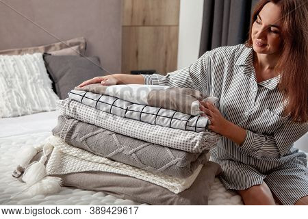 Beautiful Woman In Winter Thick Warm Robe Is Sitting And Neatly Folding Bed Linens And Bath Towels