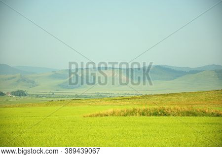 Endless Fertile Fields Flooded With Sunlight At The Foot Of The Mountain Range.