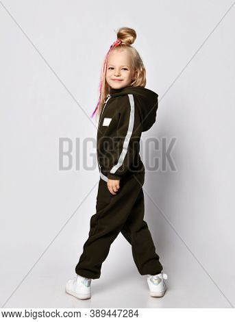 Sly Frolic Smiling Blonde Kid Girl With Braids In Stylish Brown Warm Jumpsuit With Hood And White Sn