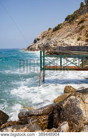 Sea Water Beats Against Rocky Rocks And Makes Waves With Foam, Rugged Pier In The Sea