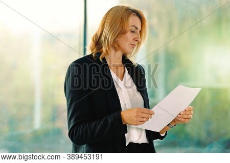 Blondine Businesswoman Holding Papers, Reads Its, Stand In Office Hallway, Confident Caucasian Profe
