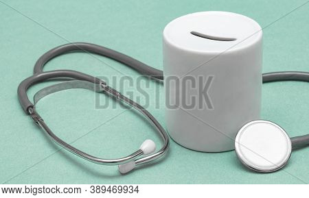 Cost Of Healthcare. Money Box With A Medical Doctors Stethoscope On Green Background