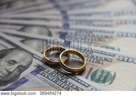 Wedding Rings On The Background Of 100 Dollars Bills. Marriage Conctract Or Prenuptial Agreement Con