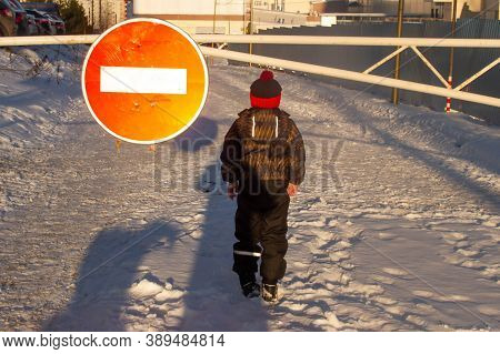 The Boy Stands In The Winter On The Road In Front Of The Sign Travel Is Prohibited. The Boy Is Afrai