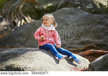 Adorable Toddler Girl Eating Her Snack In Autumn Forest. Happy Kid Enljoying Fall Day In Fontainblea