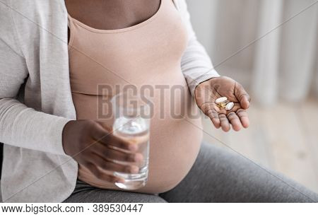 Prenatal Vitamins And Supplements. Unrecognizable Black Pregnant Woman Taking Pills Capsules And Gla