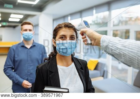 Office Workers Are Checked With A Distant Non Contact Thermometer During Coronavirus Pandemic. Young