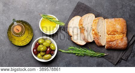 Ripe olives, olive oil and ciabatta bread. Top view flat lay