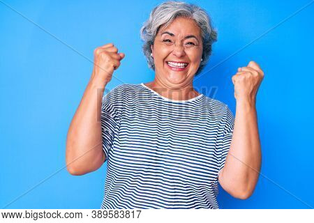 Senior hispanic grey- haired woman wearing casual clothes screaming proud, celebrating victory and success very excited with raised arms 