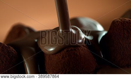 Detail of pralines with pouring melted chcocolate on top. Studio macro shot.