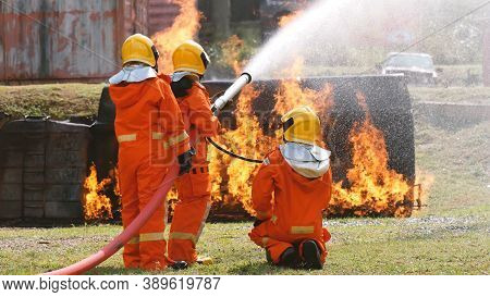 Firefighter Fighting With Flame Using Fire Hose Chemical Water Foam Spray Engine. Fireman Wear Hard