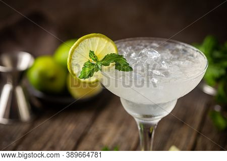 Cocktail Margarita Garnished With Lime And Mint On Wooden Background