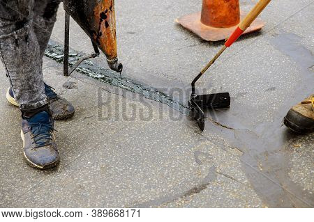 Road Surface Restoration Work In The Worker Performs Road Patcher Work Repair Of Cracks By Filling A