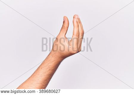 Close up of hand of young caucasian man over isolated background picking and taking invisible thing, holding object with fingers showing space 