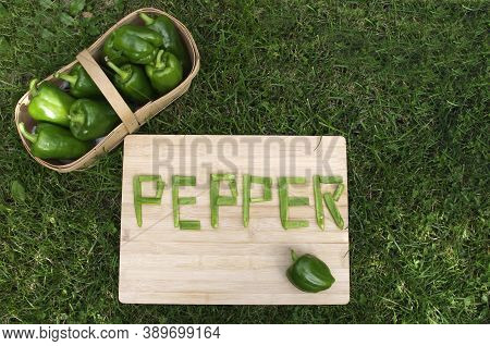 Ripe Green Peppers With Word Pepper In Pieces On Grass
