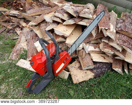 Orange Chainsaw Standing On Sawn Pine Wood