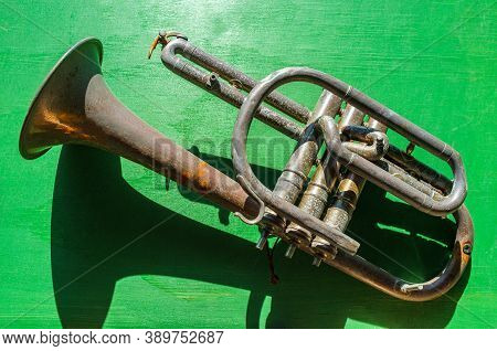 Old Rusty Antique Broken Flugelhorn On Colorful Green Background