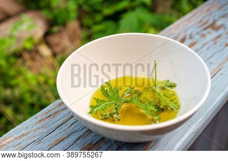 A Citronella Plant Leaf Resting In Oil To Make Homemade Mosquito Repellant