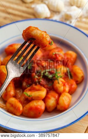 Italian Gnocchi In Red Marinara Tomato Sauce With Basil On Wooden Kitchen Table